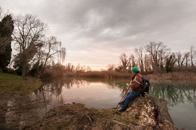 Man on rock by trees against sky