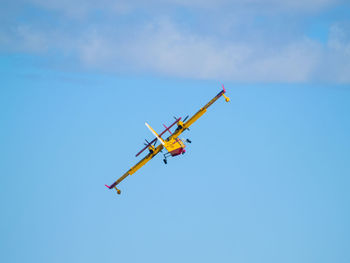 Low angle view of airplane flying against blue sky