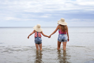 Girls walking in sea, rear view