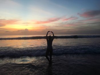 Man standing on beach against sky during sunset