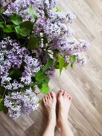 Low section of woman standing on purple flowering plant