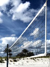 Beach volleyball net against white clouds