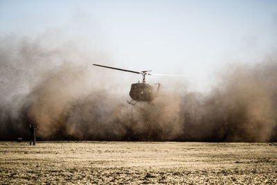 Helicopter landing over field against sky