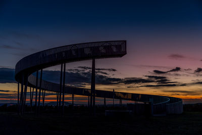 Built structure on beach against sky at sunset