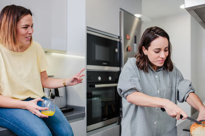 Woman preparing food while standing with friend in kitchen