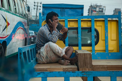 Full length of man sitting on mobile phone