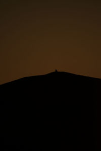 Silhouette landscape against clear sky during sunset