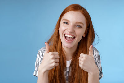 Portrait of a smiling young woman against blue background