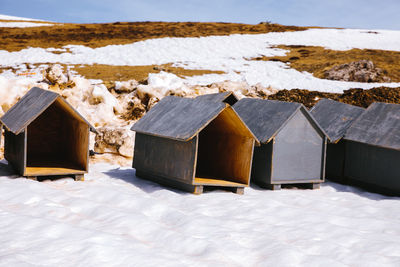 Houses on snow covered field against mountain