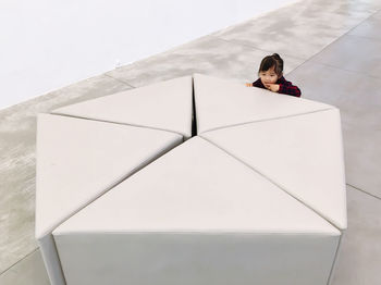 High angle view of girl behind seat on tiled floor