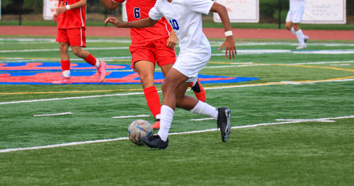 High school boys playing soccer dribbling the ball by the defender during a game.