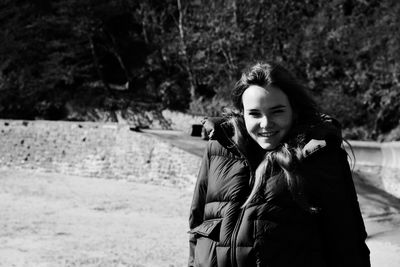 Portrait of smiling young woman in padded jacket standing outdoors