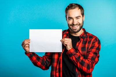 Portrait of a smiling young man against blue background