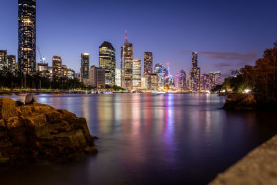 River by illuminated buildings against sky at night