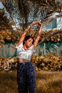 Young woman standing against trees