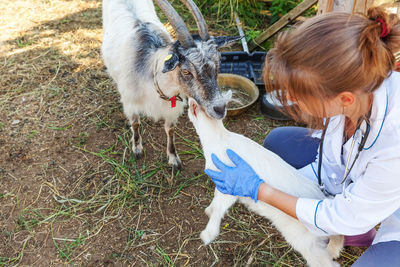 Side view of woman with goat on field