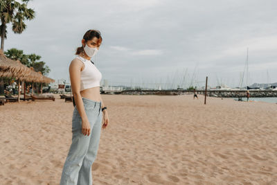 Woman standing on beach against sky