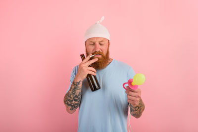 Low angle view of man holding apple against pink background