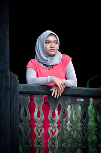 Portrait of smiling young woman standing against wall