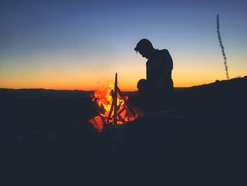 Silhouette man against orange sky