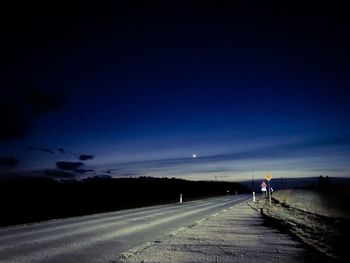 Road against blue sky at night