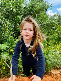 Portrait of young woman standing against plants