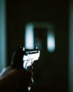 Close-up of person holding gun in darkroom