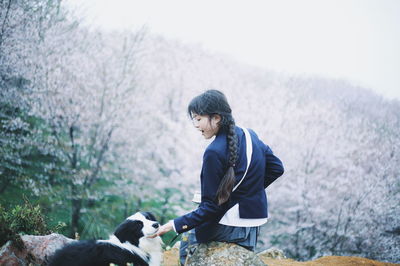 Rear view of woman with dog sitting on rock