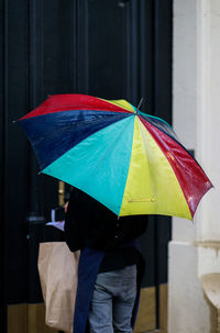 Rear view of person standing with umbrella at entrance