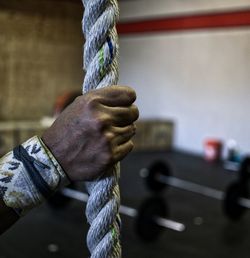 Cropped hand holding rope at gym