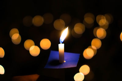 Close-up of lit candle in darkroom