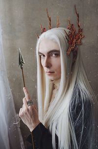 Portrait of young man wearing costume standing against wall