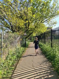 Rear view of woman running on footpath in park
