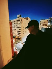 Portrait of man looking at city buildings against sky