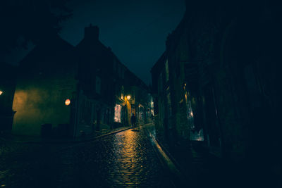 Illuminated street amidst buildings at night
