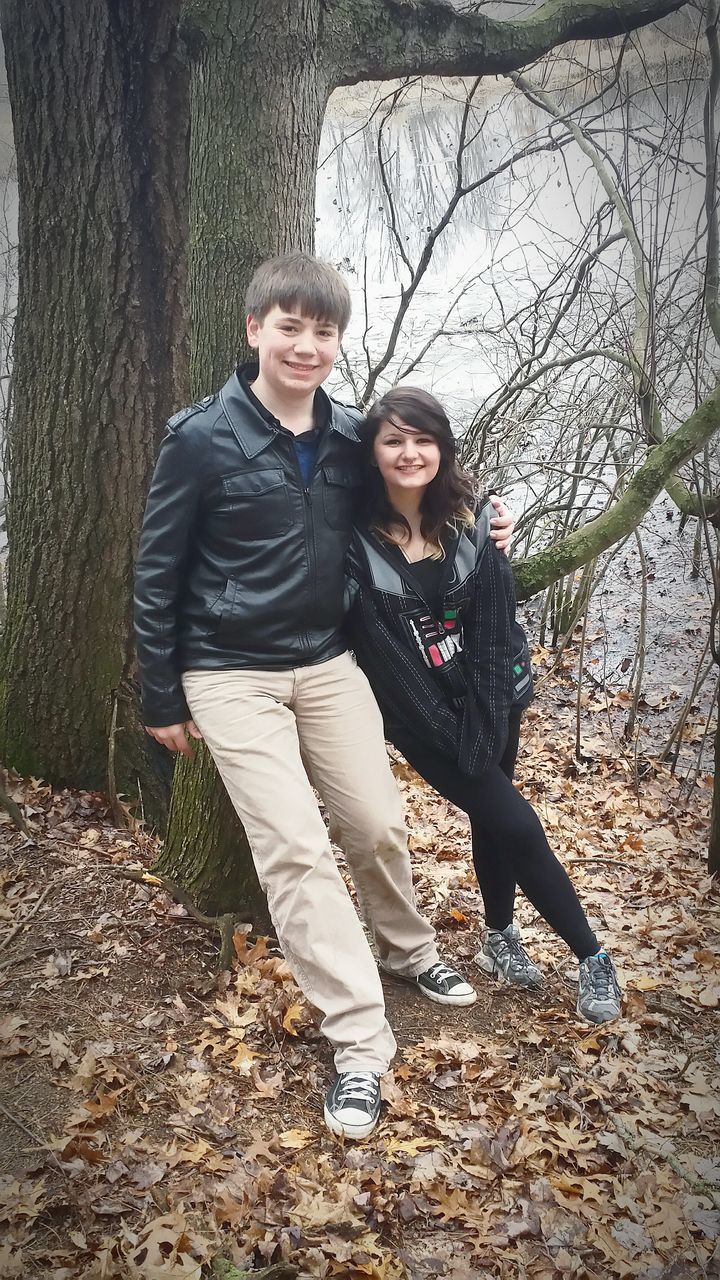 lifestyles, leisure activity, casual clothing, young adult, full length, person, looking at camera, portrait, front view, young women, standing, smiling, tree, sitting, three quarter length, leaf, happiness