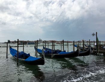 Boats in sea against cloudy sky