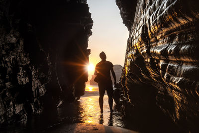 Silhouette man on rock against sky during sunset