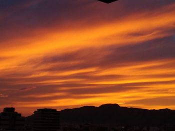 Silhouette mountain against dramatic sky during sunset