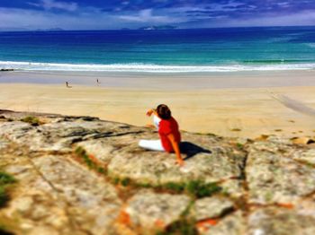 Woman standing on beach by sea against sky