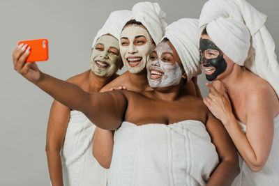 Multiethnic girlfriends taking selfie during spa session