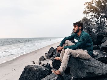 Young man sitting on rock at beach