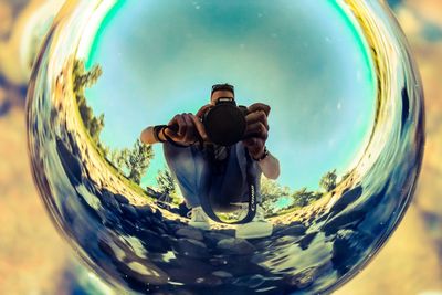 Full length portrait of man photographing reflection in sky