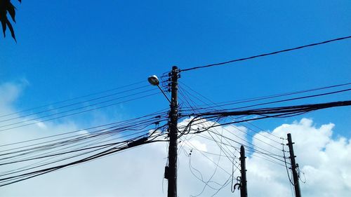 Low angle view of electricity pylon against blue sky