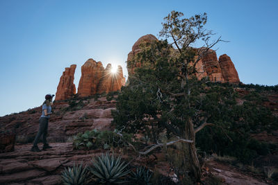 Low angle view of woman looking at rock formations against clear sky