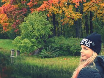 Cute girl standing by lake and trees in forest 