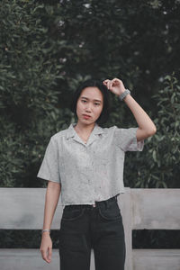 Portrait of a beautiful young woman standing against plants