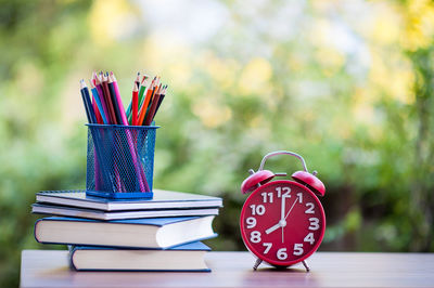 Colorful pencils with books and alarm clock on table