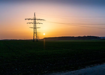 Electricity pylon on field against sky during sunset