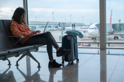 Woman works with her laptop while waiting for her flight at the airport.